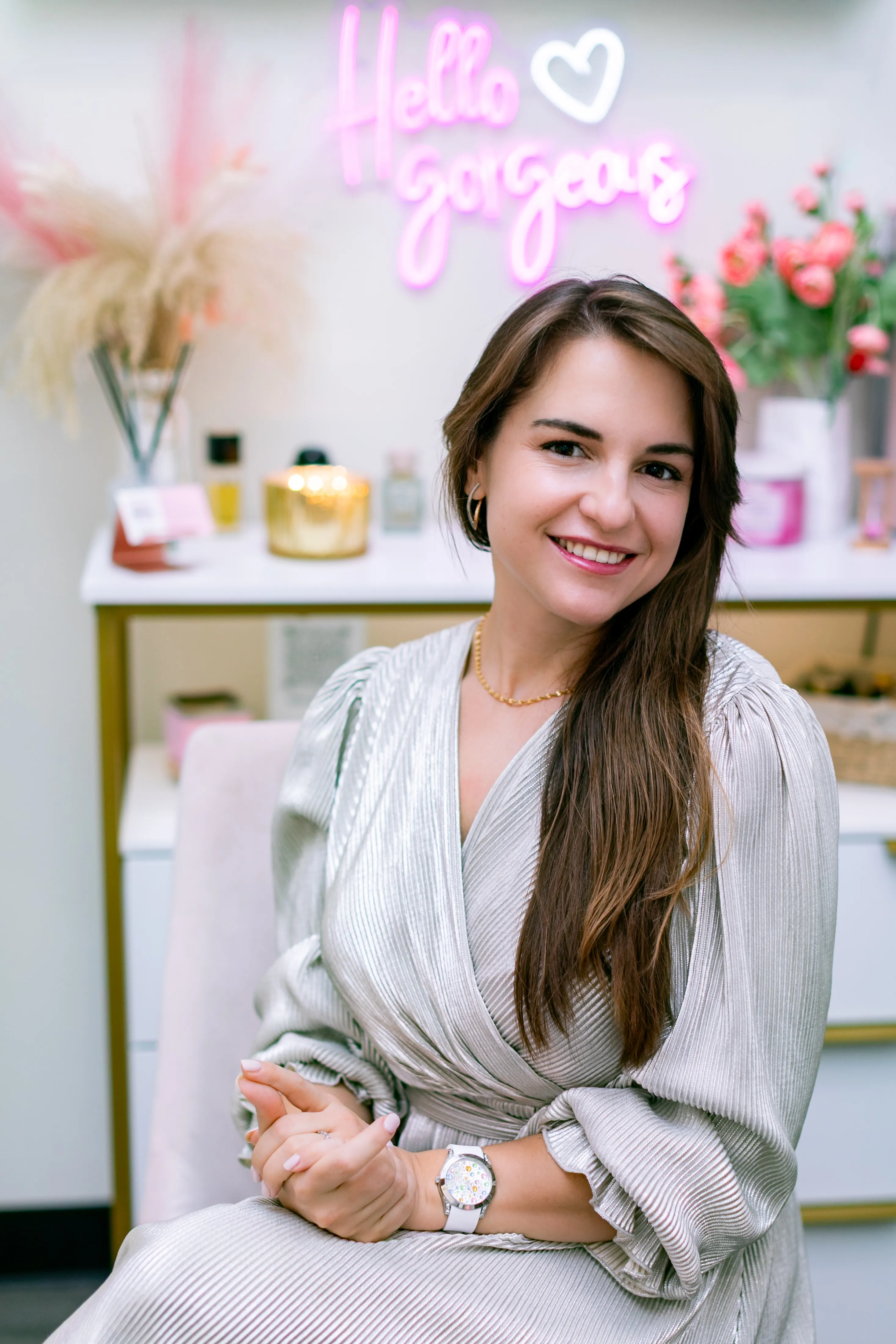 Tetiana smiling next to her pink 'Hello Gorgeous' neon sign in the studio